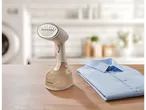 Vaporizador de roupa portátil Silvercrest e camisa azul dobrada sobre uma mesa de madeira.