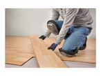 Person installing laminate flooring, wearing Parkside knee pads and work gloves.