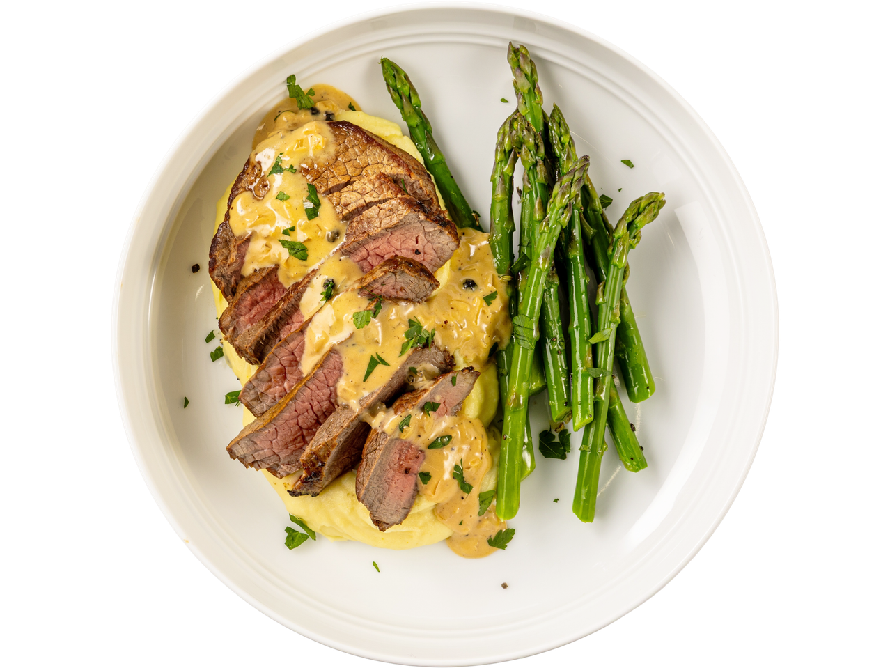 Two Irish beef medallion steaks, sliced and drizzled with sauce, served with mashed potatoes and asparagus.