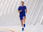 Man in blue running shirt and shorts jogging outdoors.