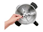 Hand holding a blender blade inside a stainless steel mixing bowl with measurement markings.