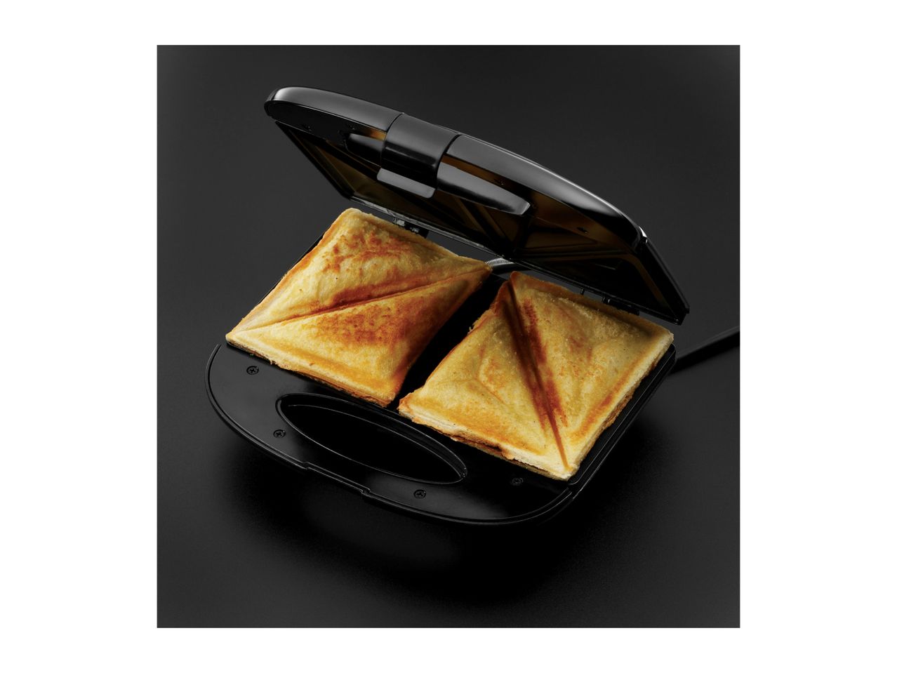 Open sandwich maker with two golden-brown toasted sandwiches inside, on a dark background.