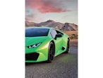 Zöld Lamborghini Huracán egy sivatagi úton, hegyekkel és rózsaszín égbolttal a háttérben.