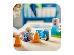 Child playing with a toy police officer, motorcycle, traffic cones, and traffic light.