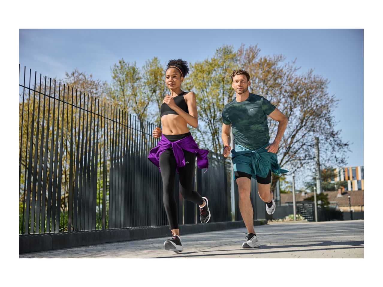 Two people running outdoors, wearing sports tops, leggings, and shorts.