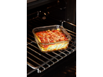 Vas de copt cu lasagna cu sos de roșii și brânză în cuptor.