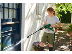 Woman pressure washing a blue door and white wall with a green pressure washer.