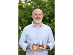 Man holding two Steeper Culture kombucha cans: Ginger & Lemon and Cherry Lime.