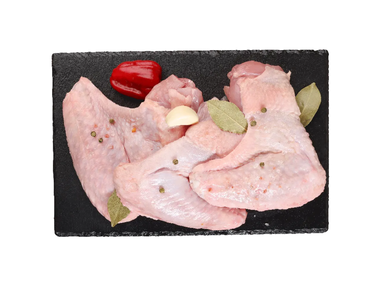 Sveža pileća krilca sa belim lukom, lovorovim listom i crvenom paprikom na crnoj podlozi.