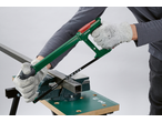 Homem com luvas a cortar perfil metálico com serra manual PARKSIDE numa bancada.