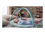 Baby on a playmat with hanging toys, including a bear, watermelon, and alligator.