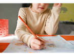 Un copil desenează cu un creion colorat BIC.