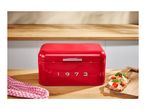 Red retro bread bin with the year 1973 on a wooden kitchen counter.
