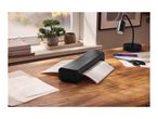 Black laminator on a wooden desk, laminating a document, with office supplies nearby.