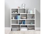 A white modular shelving unit filled with books, plants, decorative items, and storage boxes.