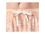 Close-up of a woman's midsection wearing peach-colored shorts with a tropical leaf print.