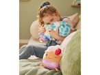 A young girl hugging two plush toys, with a cupcake plush toy in the foreground.