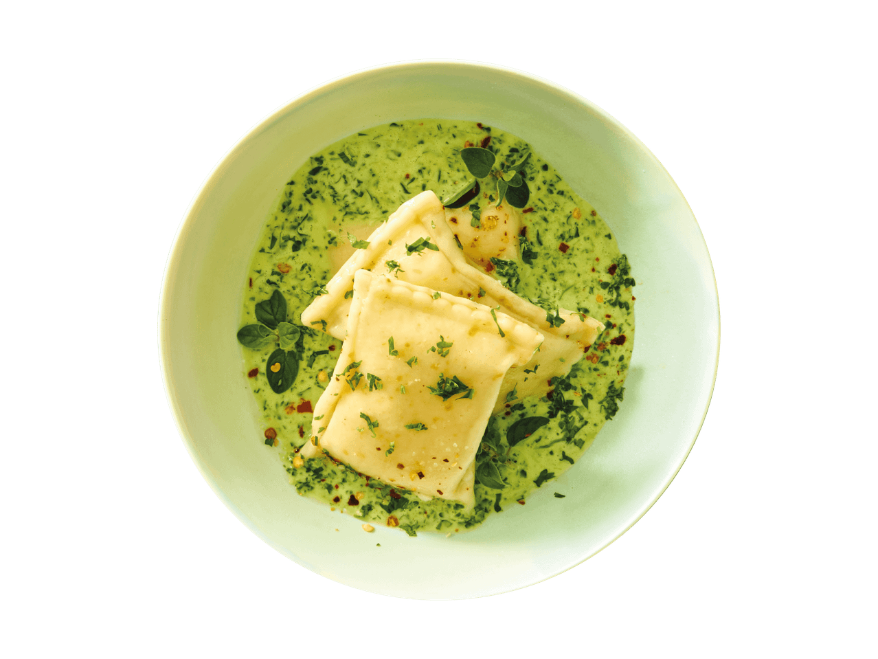 Ravioli in grüner Soße mit Kräutern und Chiliflocken in einer Schale.