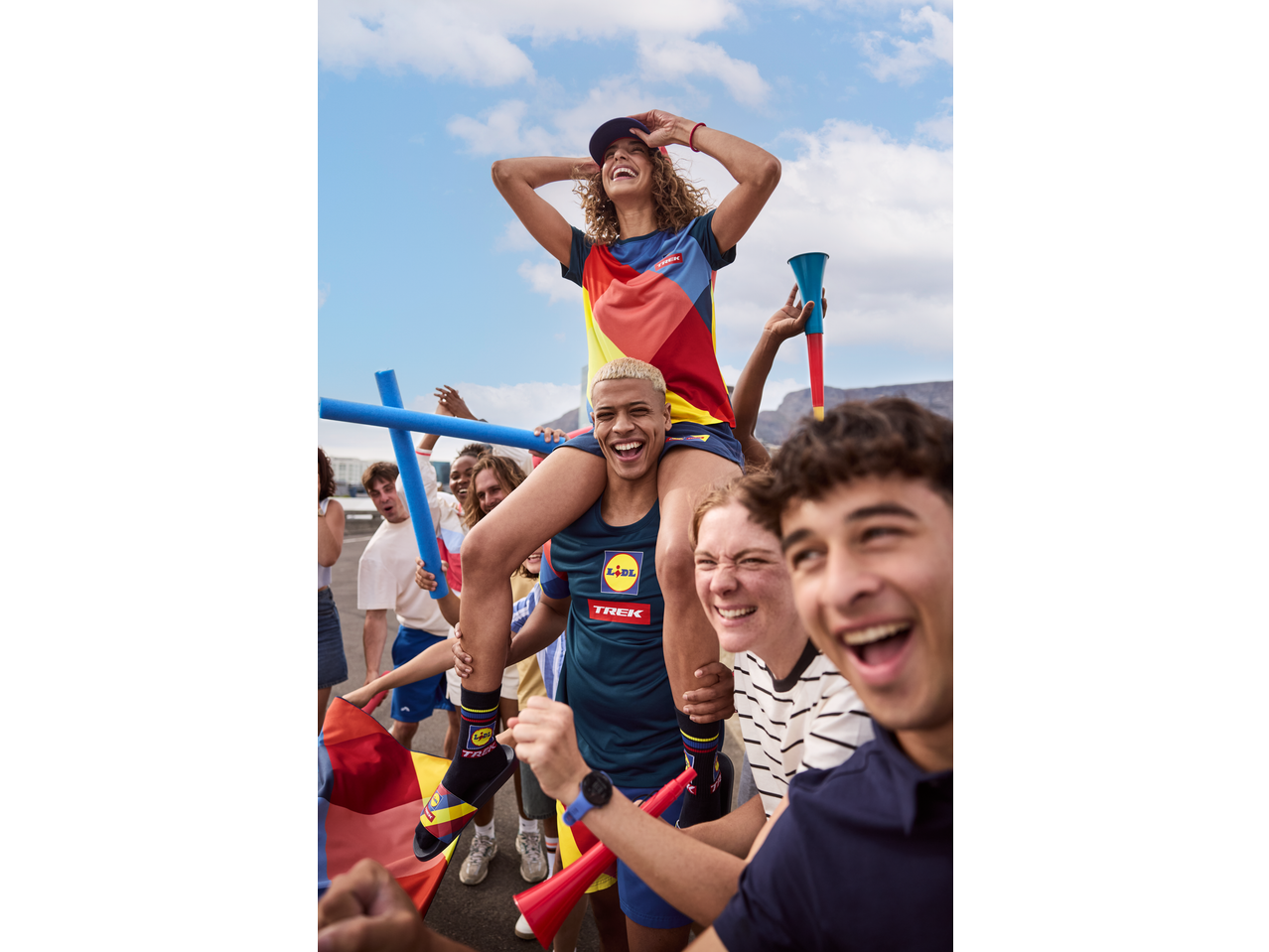 Grup de tineri care încurajează, o fată pe umerii unui băiat, ambii purtând șosete CRIVIT.