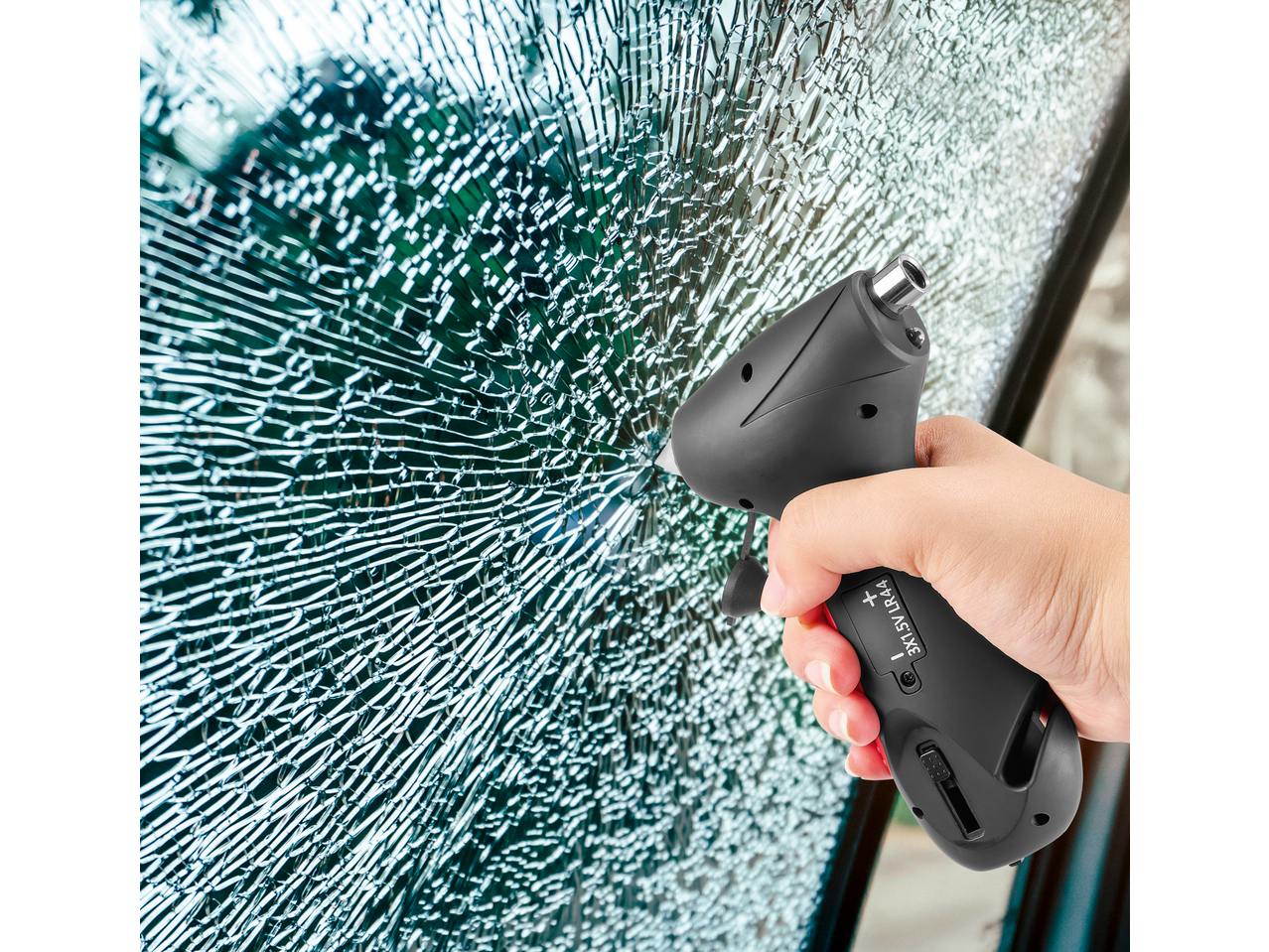 Hand holding a 5-in-1 tyre pressure gauge against a shattered car window