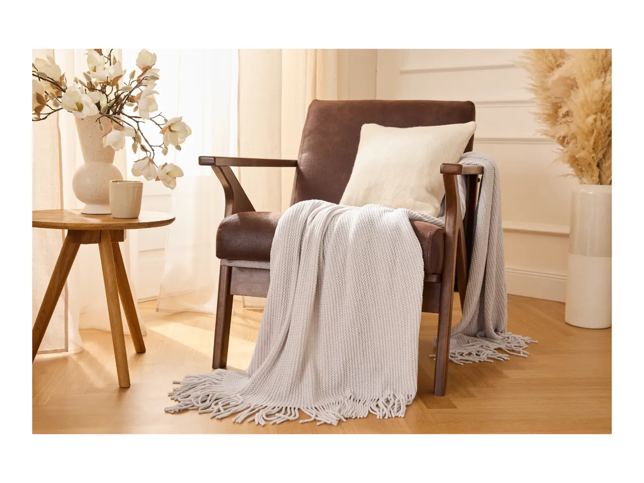 Cozy brown armchair with a soft throw blanket and cushion in a warm, modern living room.