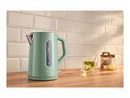 Mint green kettle on a wooden counter with a cup of tea and lemon slices.