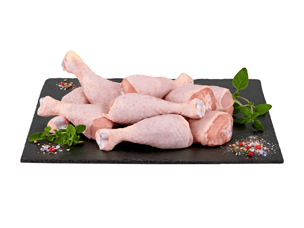Rohe Hähnchenunterschenkel auf einer schwarzen Schieferplatte mit Kräutern und Gewürzen.