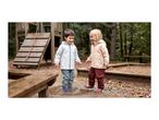 Two happy children in waterproof jackets and trousers splashing in a puddle.