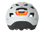 Бяла велосипедна каска с червена задна светлина и бутон за включване/изключване.