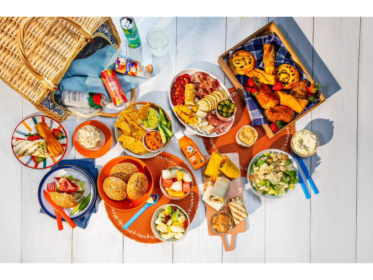 Summer picnic with sandwiches, croissants, salad, and Sanbitter & Black Forest drinks.