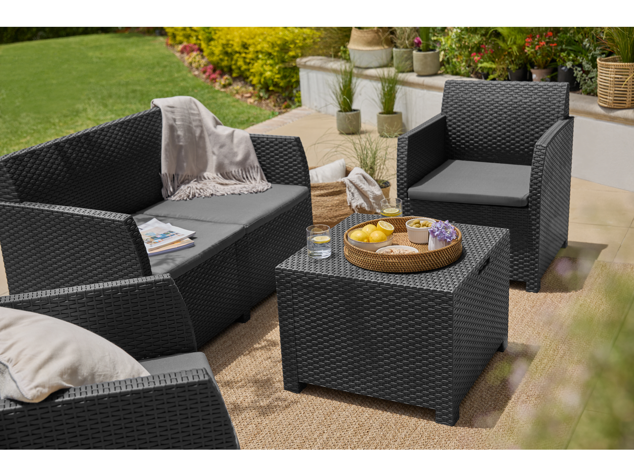 Livarno Garden Sofa Set with dark grey cushions and a coffee table on a patio.