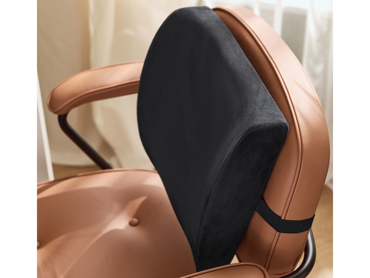 Black lumbar support cushion on a brown leather office chair.