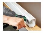 A person using a right-angle drill attachment to drive a screw inside a narrow plastic channel