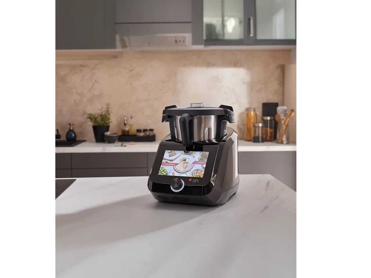 Robot de cuisine multifonction noir avec écran tactile affichant des recettes, sur un comptoir de cuisine.
