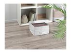 White storage box with lid, filled with folded clothes, on a wooden floor next to a shelf.