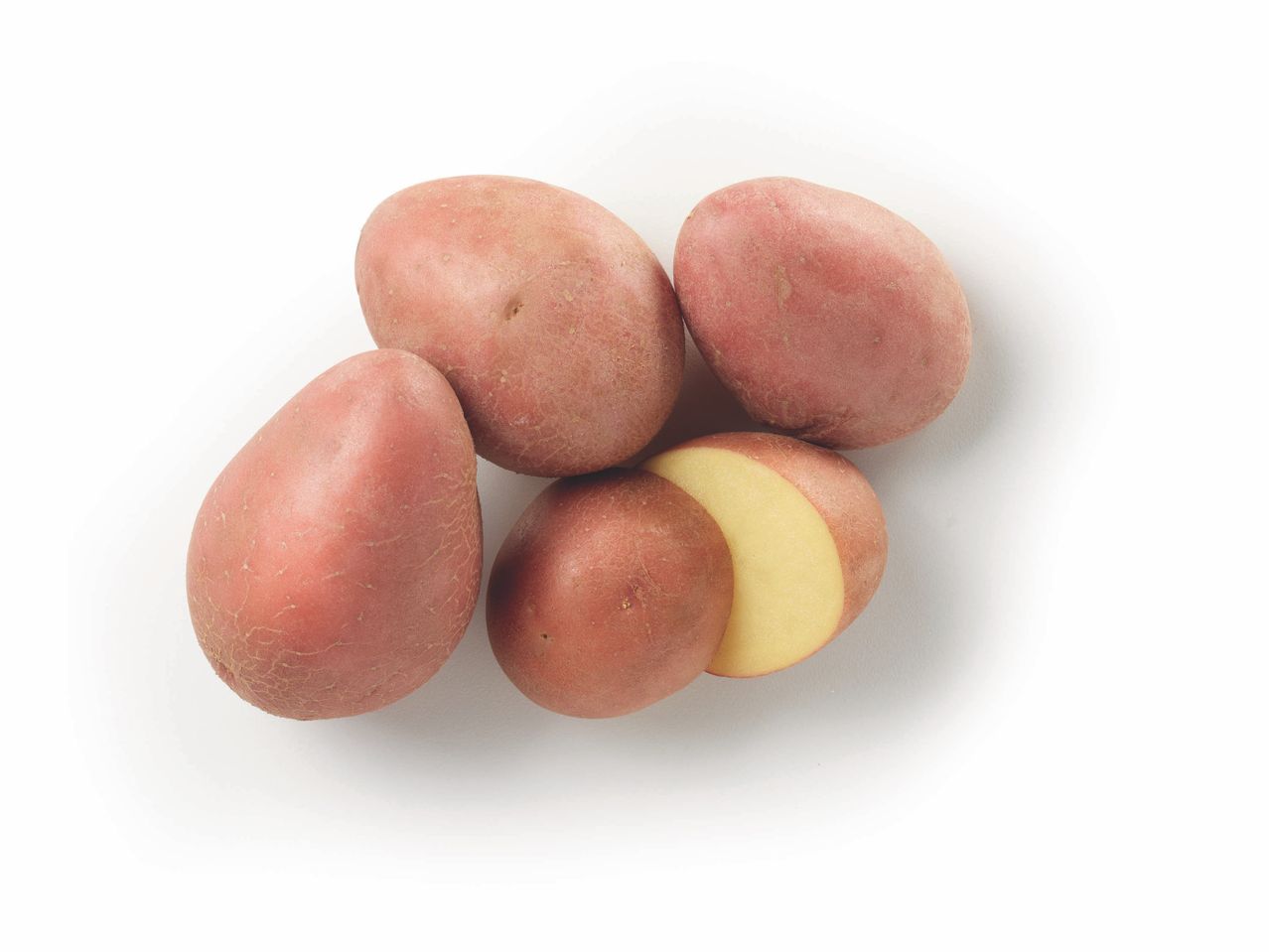Four red potatoes, one cut in half, showing creamy interior.