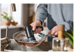 Une personne lave une poêle avec une brosse de nettoyage électrique dans un évier de cuisine.