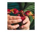 Child's hands holding a red and gold toy robot with a small figure inside, against a green background.