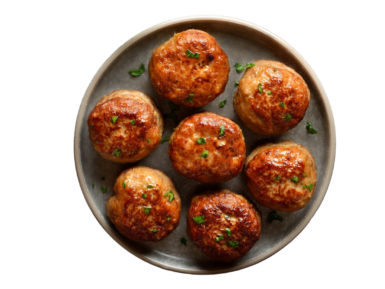 Taldrikul olevad kuldpruunid lihapallid, kaunistatud roheliste ürtidega.