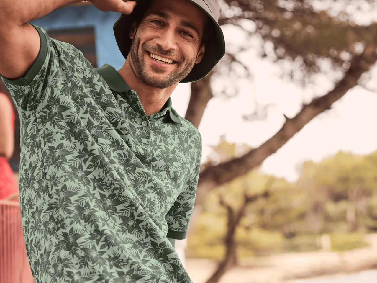 Mann in grünem Poloshirt mit Muster und Fischerhut.
