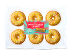 Zes mini donut cakes met citroenglazuur en gekleurde sprinkles in een plastic verpakking.