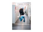 Child with backpack jumping in a school hallway.