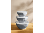 Stack of three grey mixing bowls with white lids on a wooden surface.