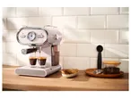 Pink SilverCrest espresso machine brewing coffee into two glasses on a wooden counter.