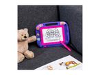 A Paw Patrol drawing board with a teddy bear and a book on a gray couch.