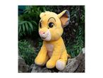 A plush toy of a lion cub sitting on a log amidst green foliage.