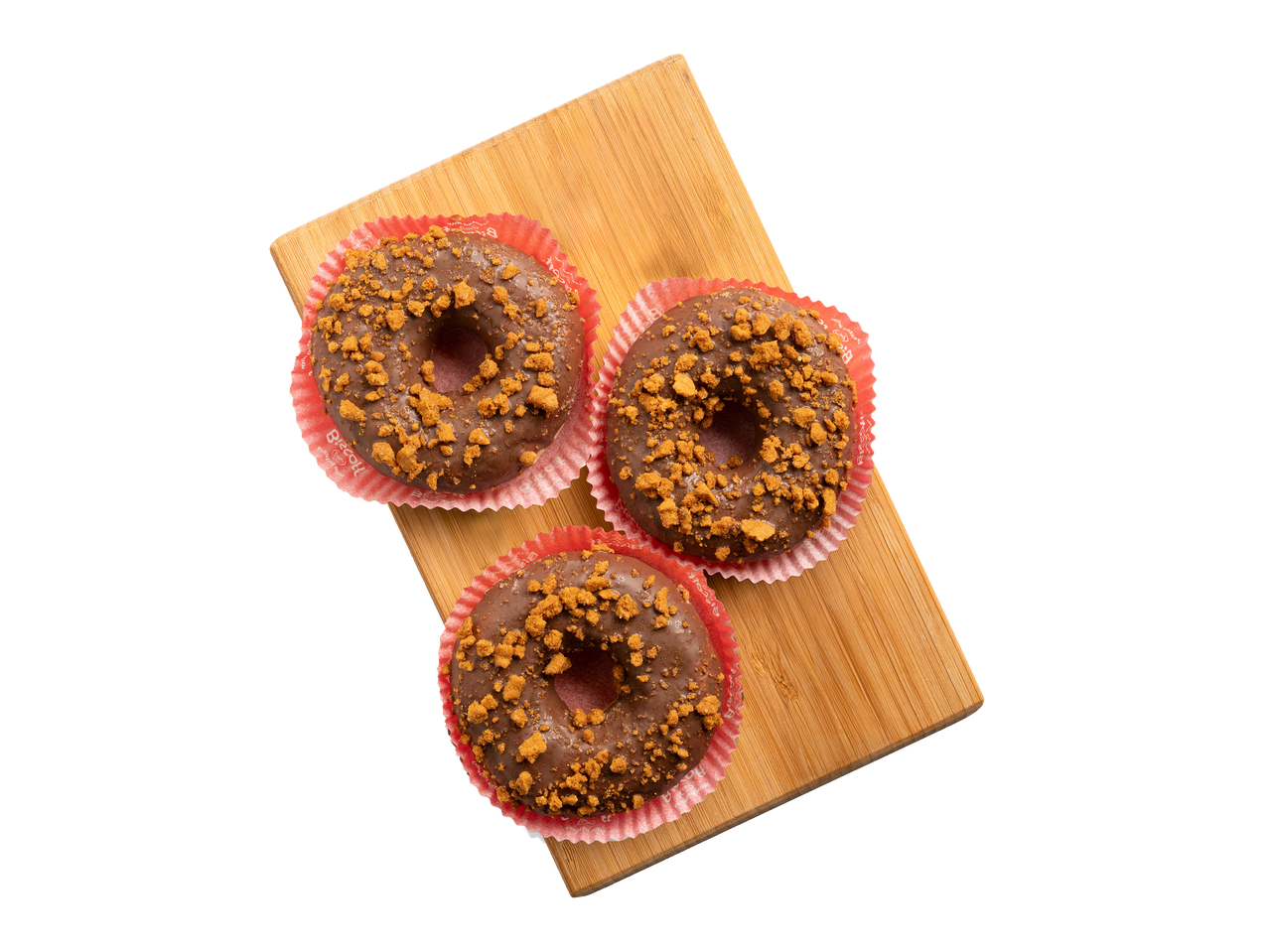 Három csokoládé fánk kekszdarabokkal, piros papírkosárban, fa deszkán.