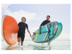 Two people run through the water with inflatable paddleboards.