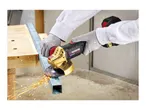 Cordless angle grinder cutting metal, creating sparks, on a wooden workbench.
