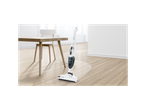 Bosch cordless vacuum cleaner on a light wood floor next to a dining table.